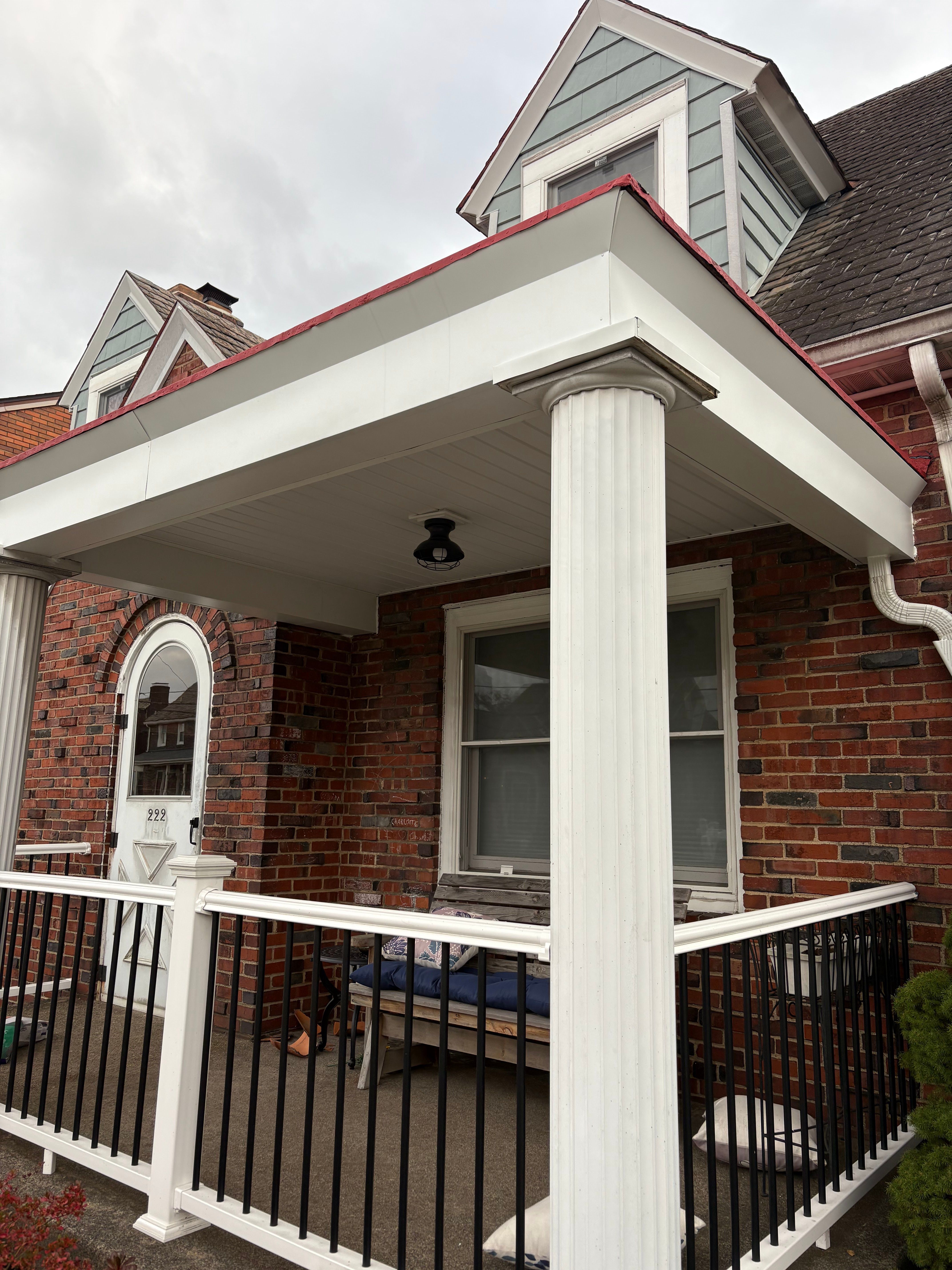 Front porch with white columns and black railing on a brick home