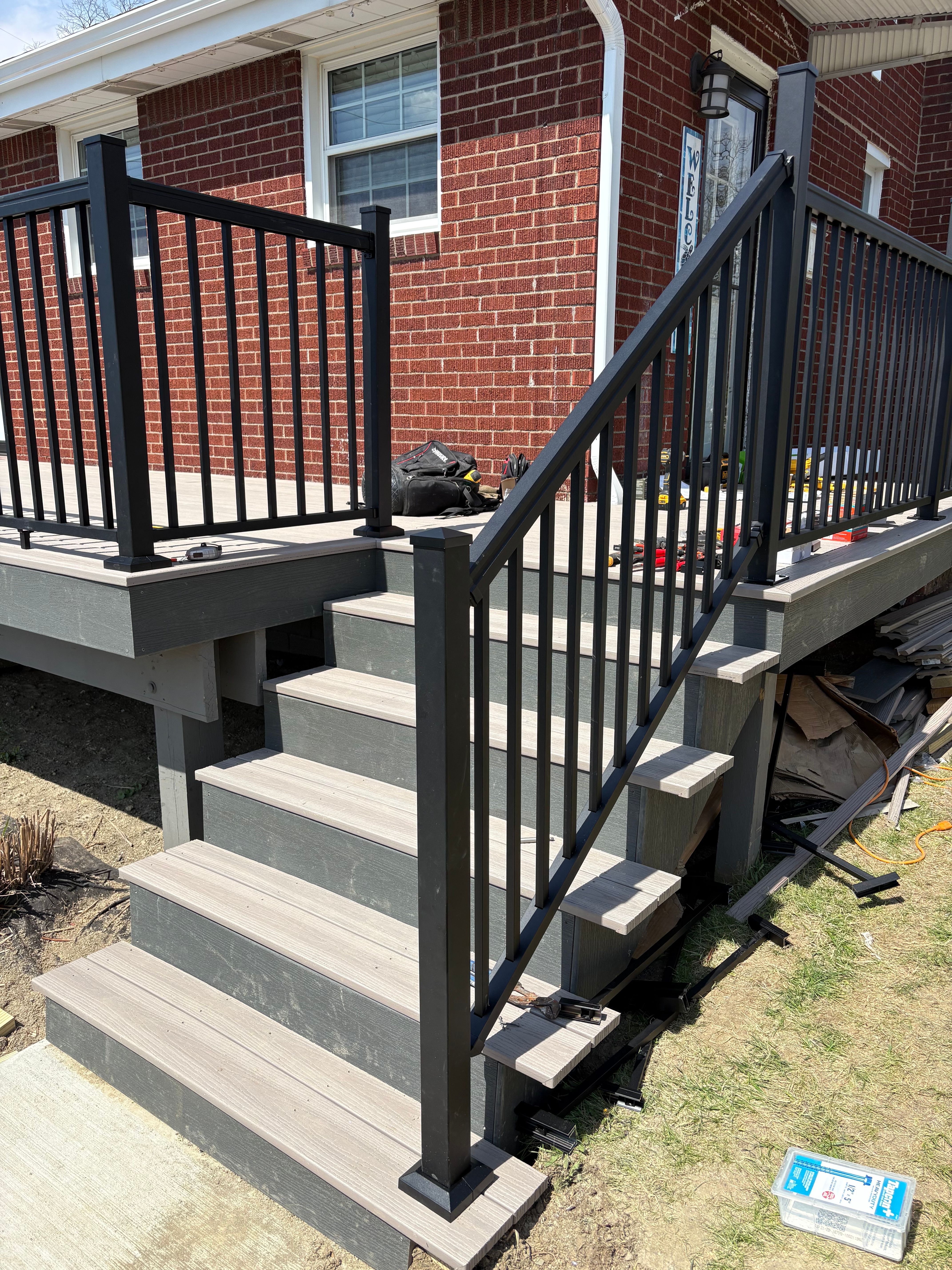 Composite steps with black railing leading down to a concrete walk