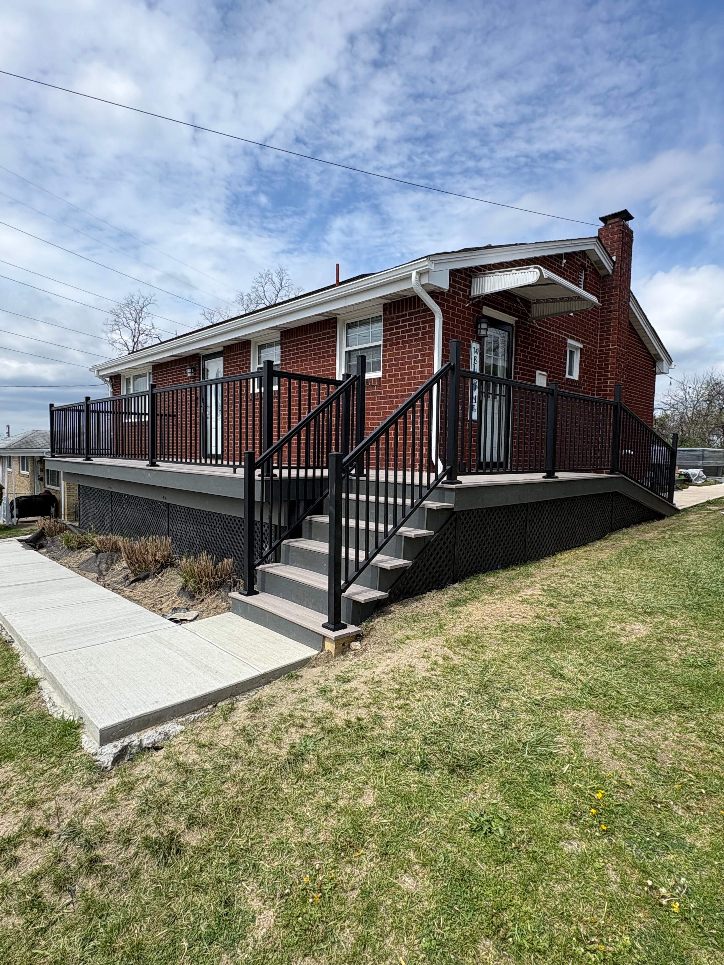 Black aluminum railing along a deck and steps at a brick ranch