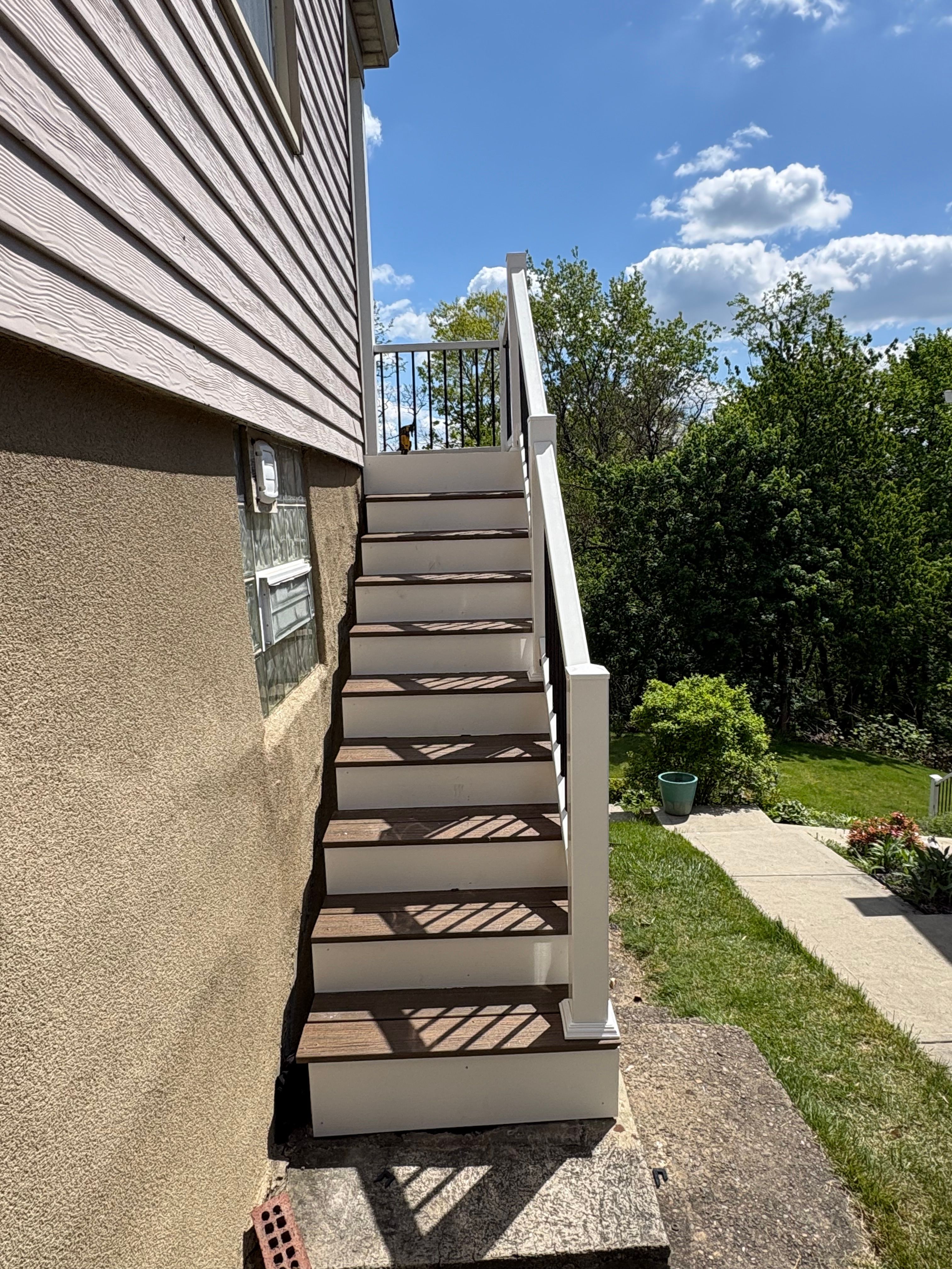 Composite staircase with white railing along the side of a home