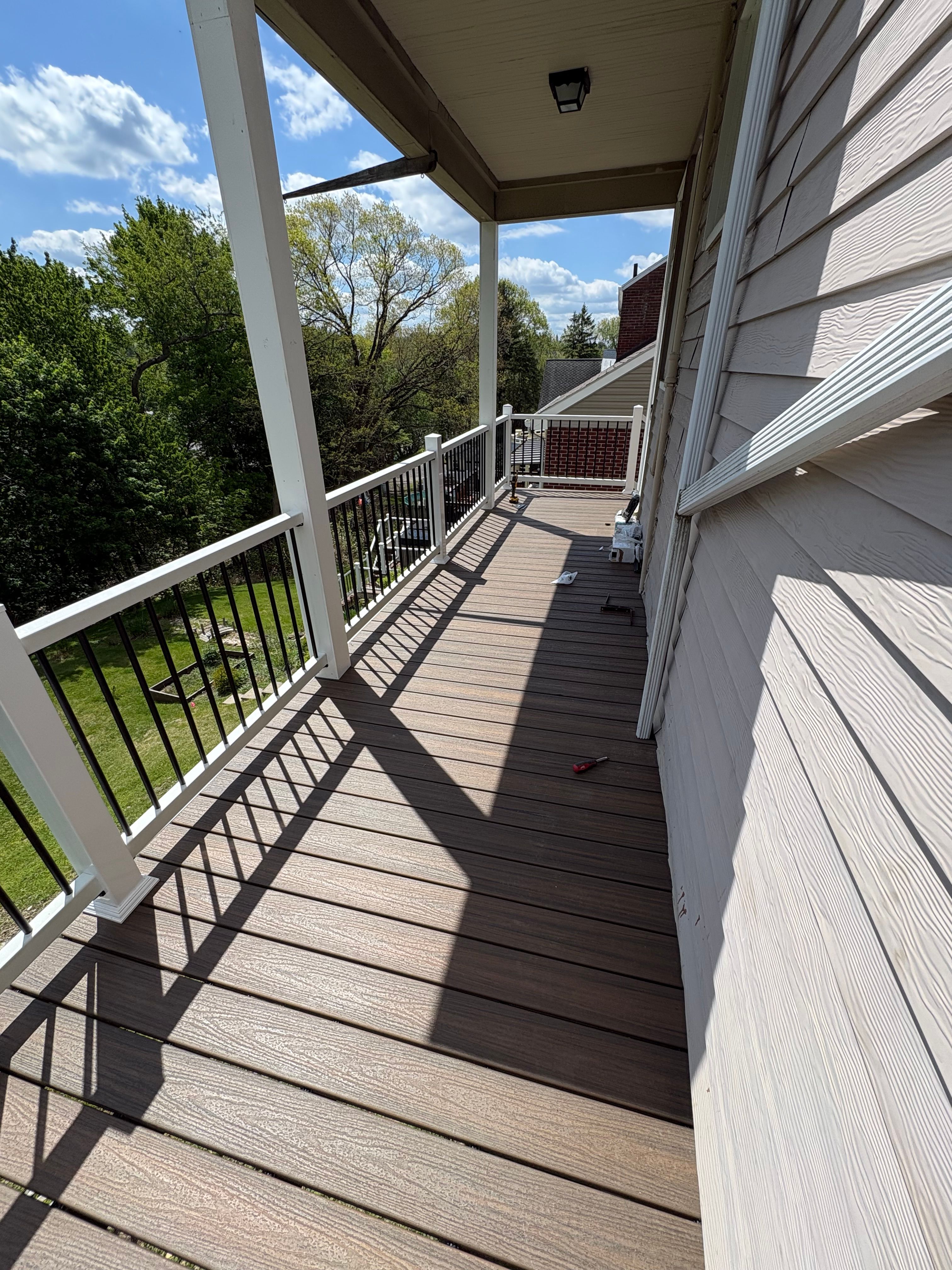 Covered deck with brown composite decking, white posts and black aluminum railing