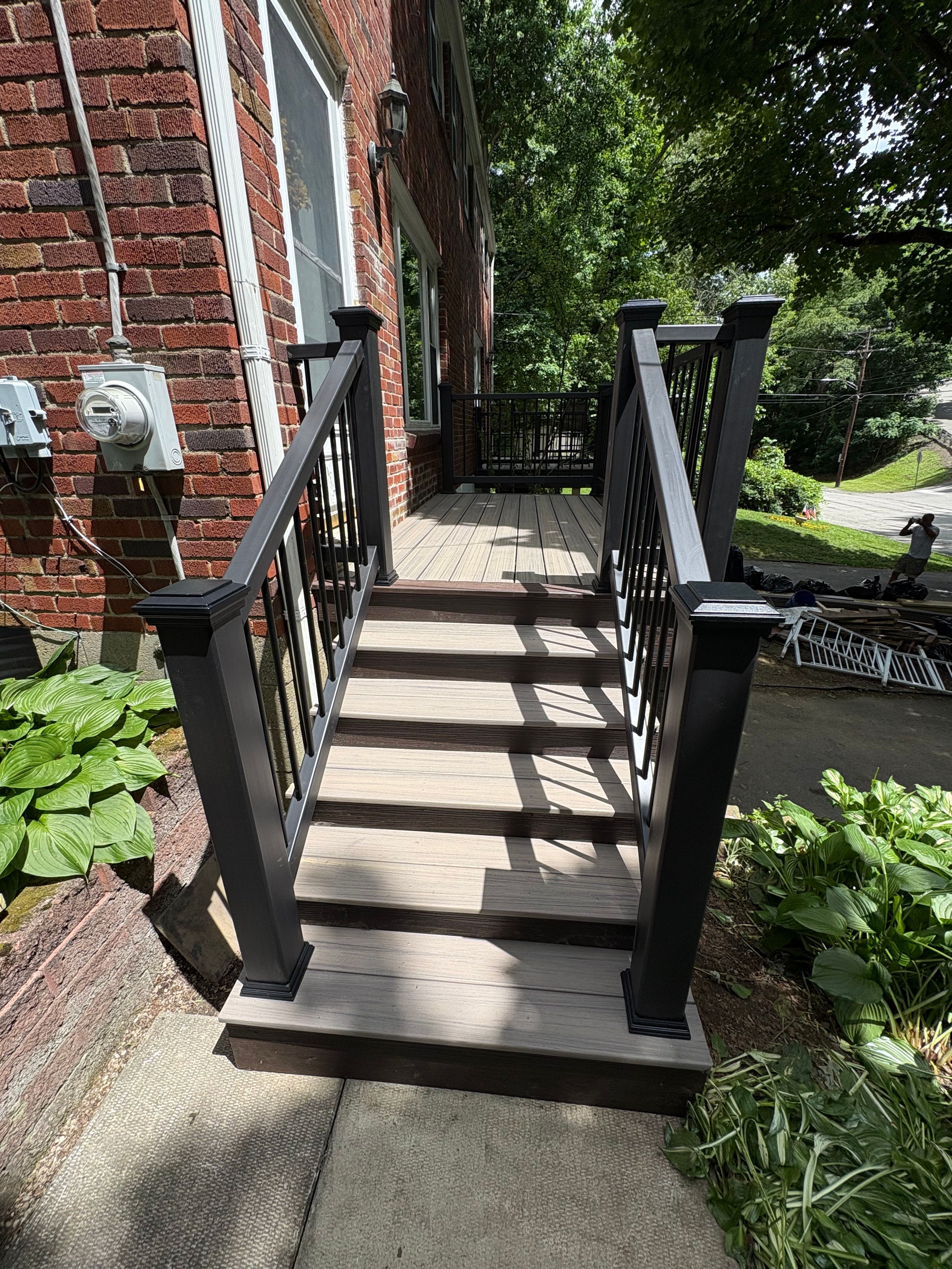 Composite steps with black railing down to the front walk