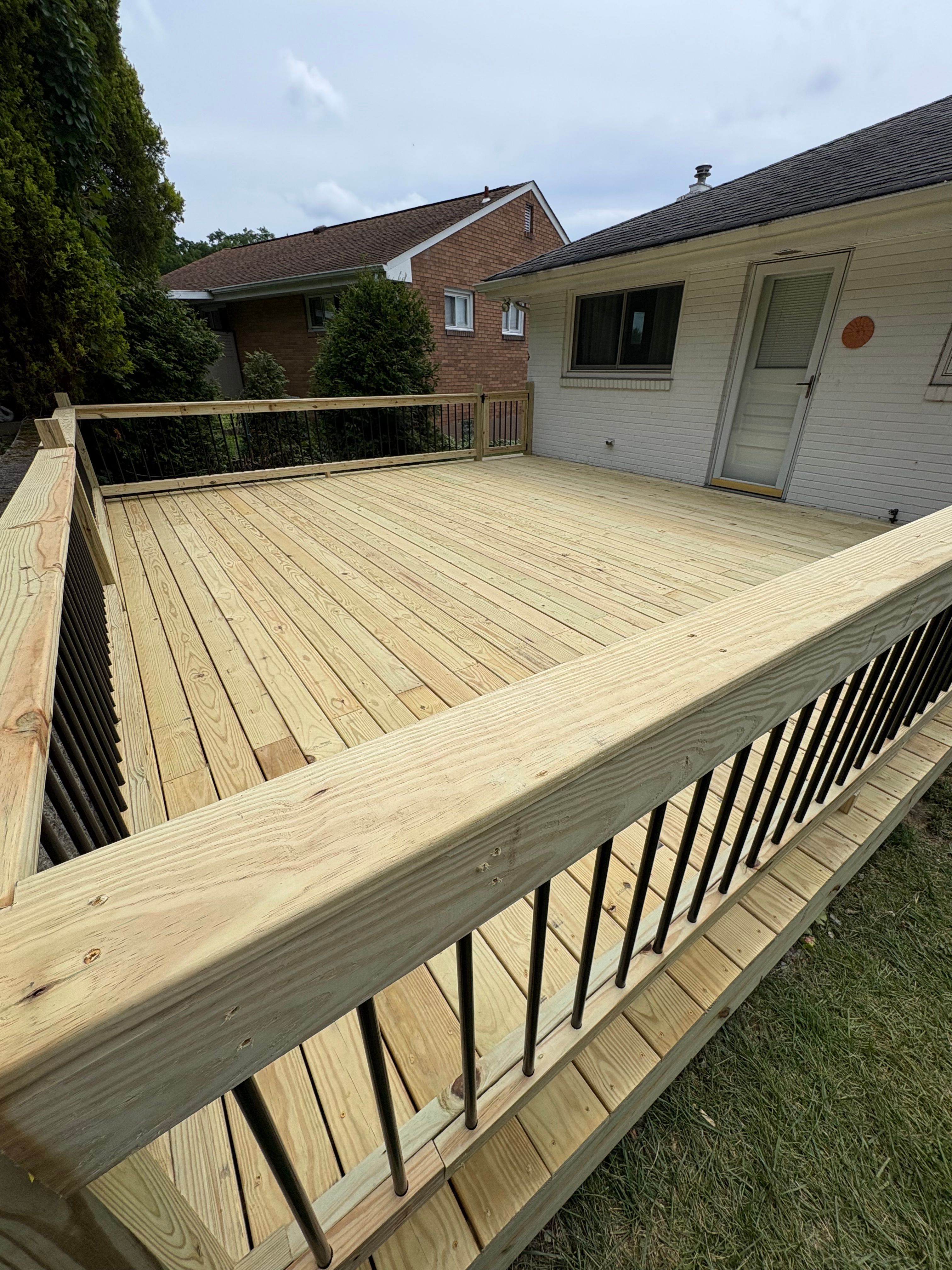 New pressure treated deck with railing running the length of the house