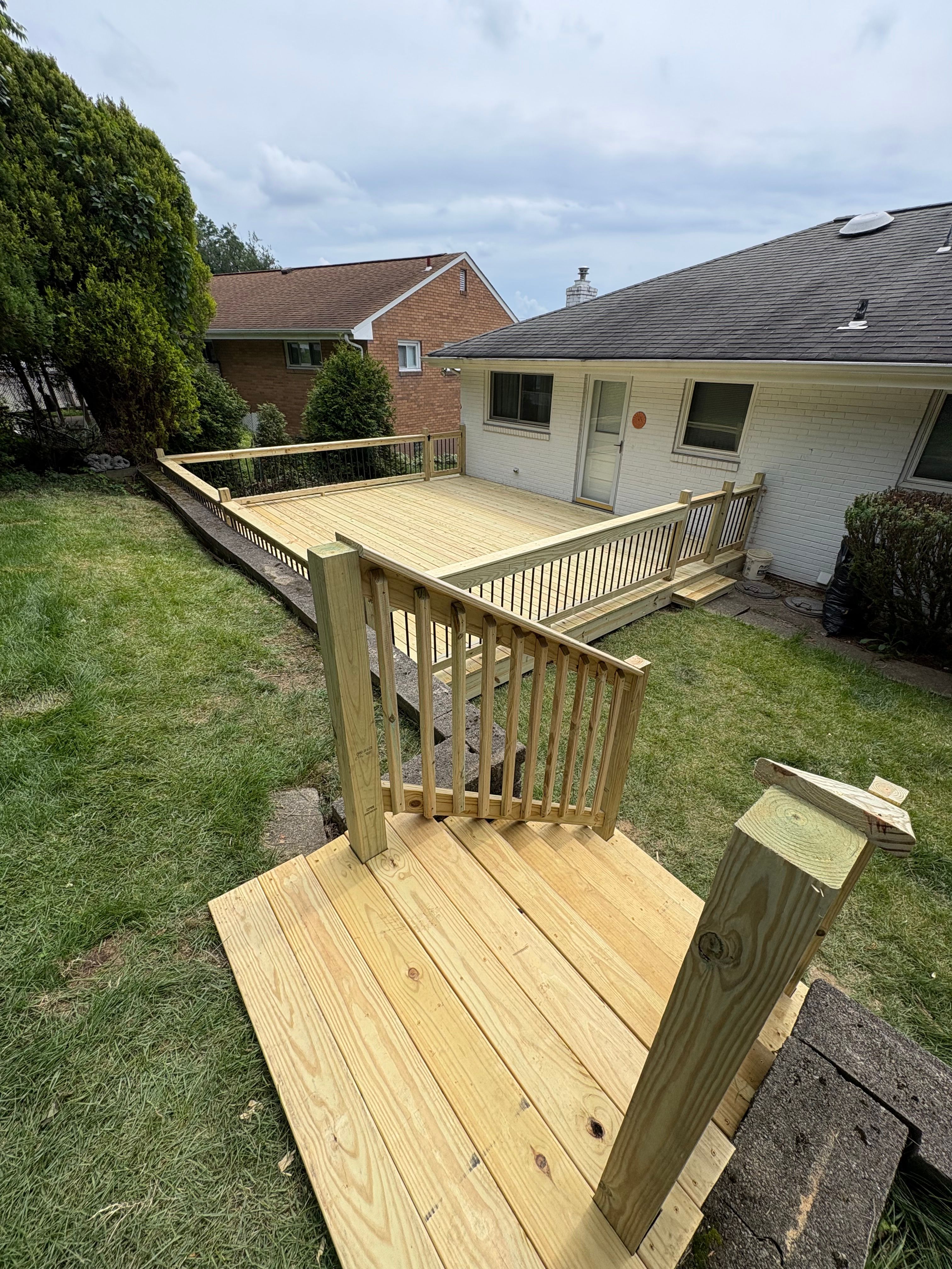 New pressure treated deck and steps down to the lawn at a brick ranch
