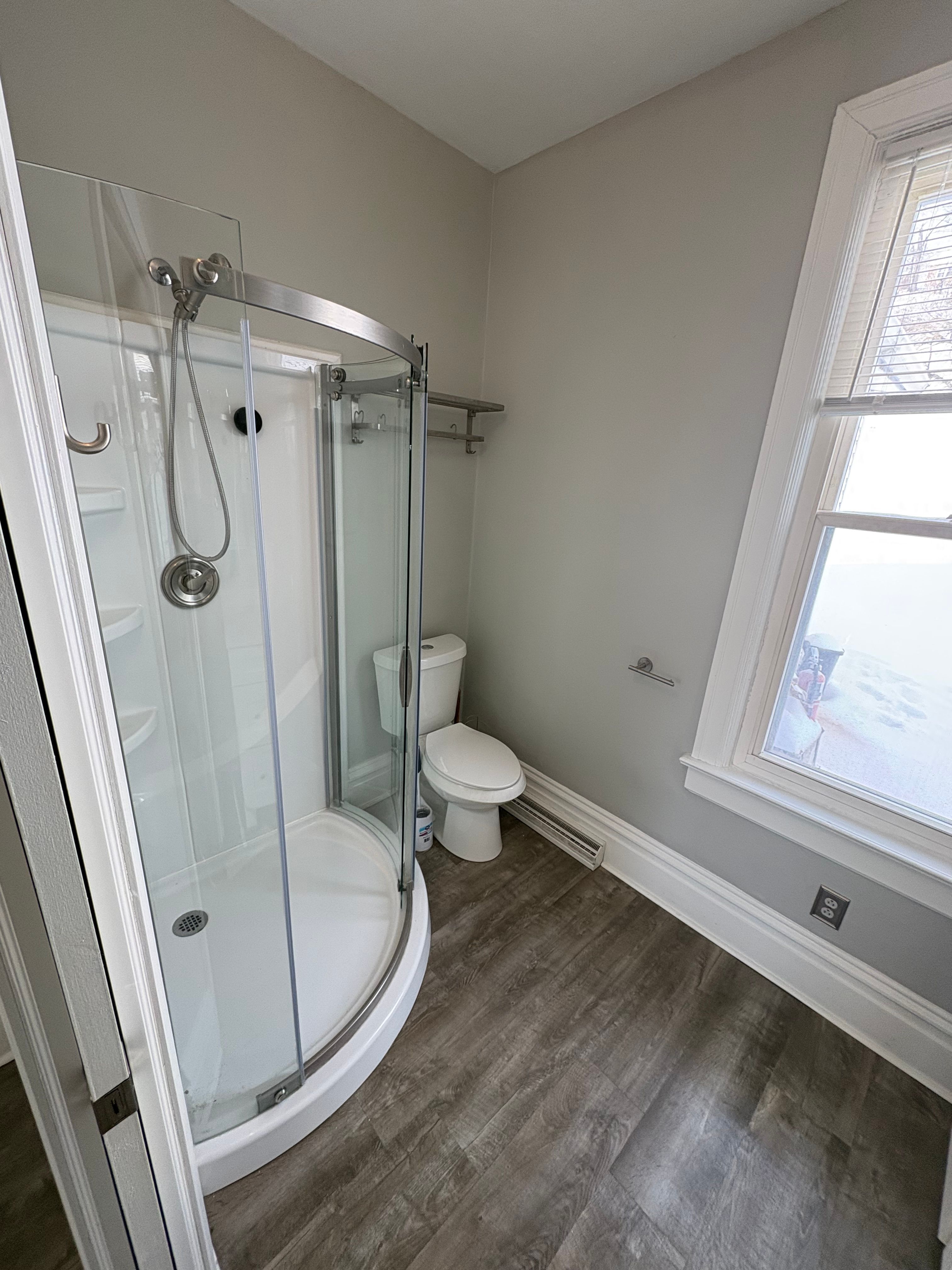 Finished bathroom with a corner shower unit and new flooring