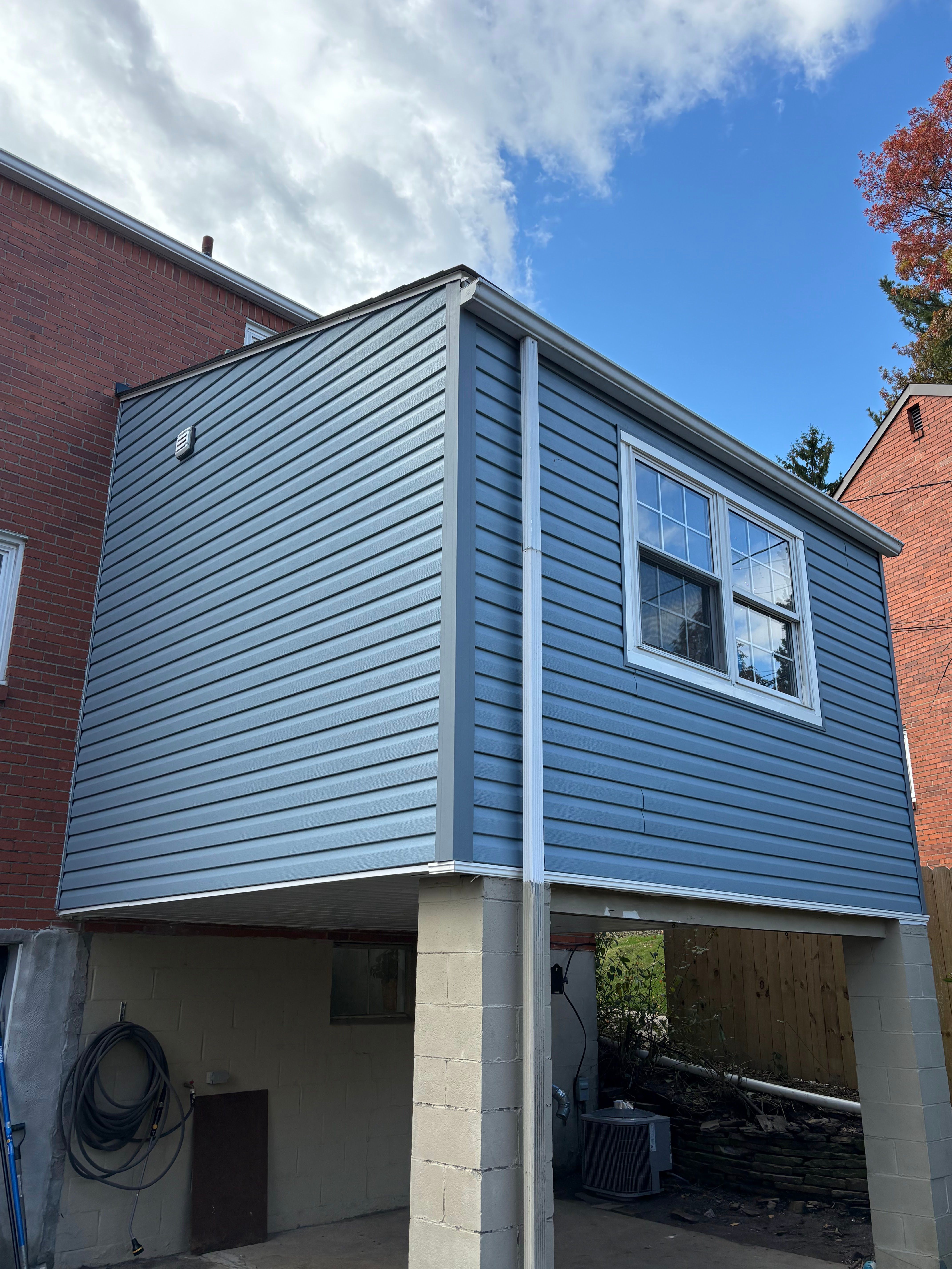 Blue vinyl siding on a second storey addition above a carport