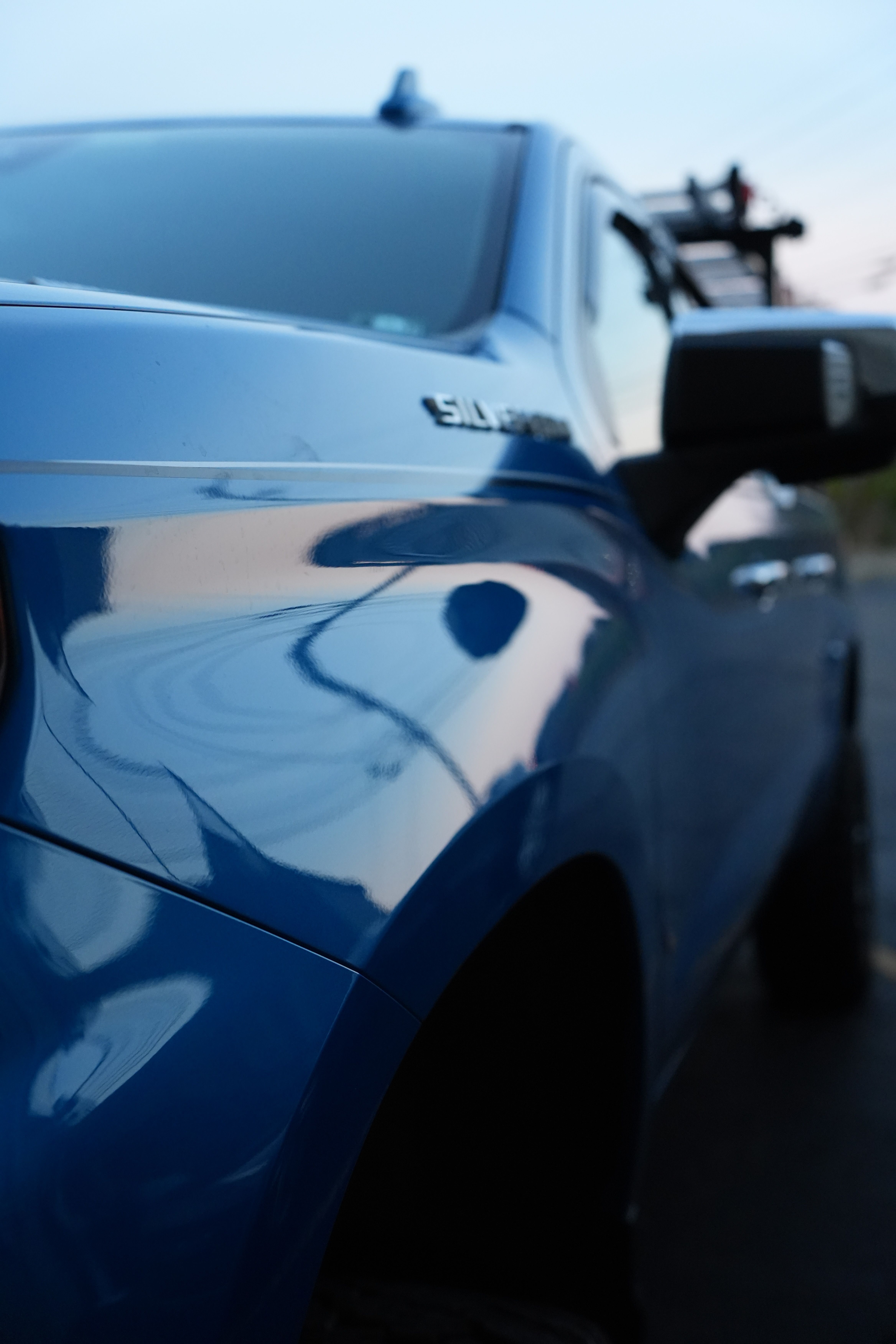 Close view along the side of a blue Chevrolet Silverado with a ladder rack on the roof